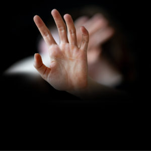 Frau hält sich schützend die Hände vor den Körper.