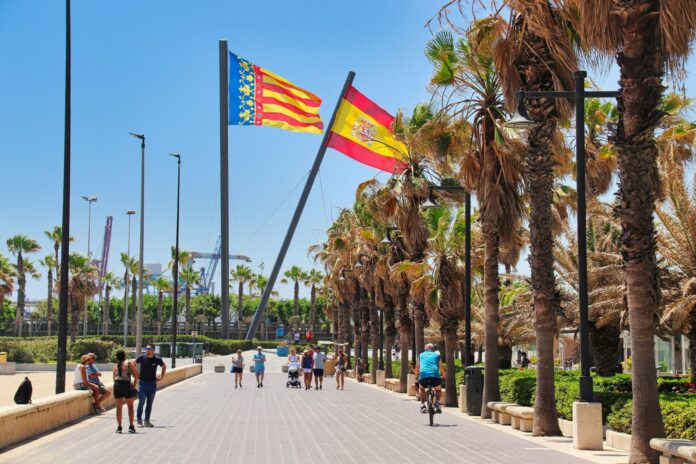 Un groupe de personnes marche le long d'une route à côté de palmiers à Valence en Espagne.