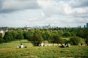 Personen in Park mit Skyline von London im Hintergrund.