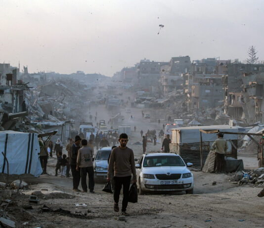 Le Conseil des États renonce à supprimer les fonds de l’UNRWA Des personnes marchent au long d'une route dans la bande de Gaza, complètement détruite