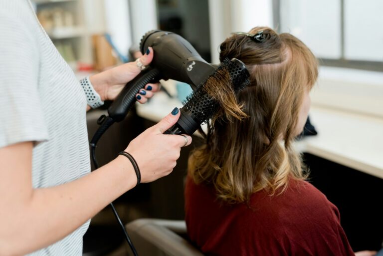 Une coiffeuse sèche les cheveux d'une cliente avec une brosse ronde.