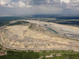Glencore au défi de fermer la mine de Prodeco en Colombie Vue aérienne d’une vaste carrière à ciel ouvert creusée en terrasses successives, avec un petit plan d’eau au fond. Les contours de l’excavation forment des courbes régulières, contrastant avec la ceinture de forêt et de champs qui l’entourent, le tout sous un ciel nuageux.