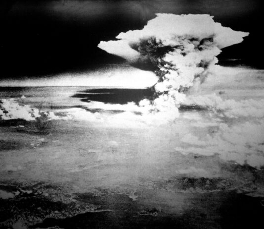 80 ans après Hiroshima et Nagasaki : le monde a besoin d’une interdiction des armes nucléaires Photographie en noir et blanc prise depuis les airs : un vaste nuage en forme de champignon s’élève au-dessus de Hiroshima.