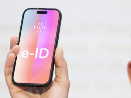 e-ID : l’identité électronique publique indépendante des multinationales de la tech’ Un homme tient un smartphone sur lequel apparaît en grand le mot ‹e-ID›. L’image illustre l’identité électronique prévue en Suisse