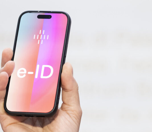 e-ID : l’identité électronique publique indépendante des multinationales de la tech’ Un homme tient un smartphone sur lequel apparaît en grand le mot ‹e-ID›. L’image illustre l’identité électronique prévue en Suisse