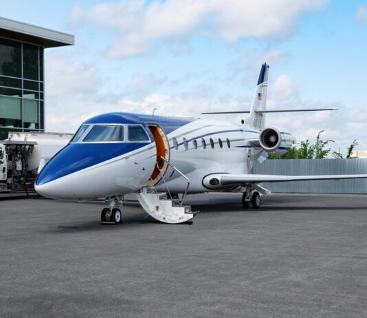 Amsterdam : l’aéroport Schiphol interdit les jets privés à partir de fin 2025 Un jet privé bleu et blanc dans un aérodrome.