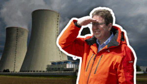Albert Rösti, un homme en veste orange et lunettes se tient devant deux grandes tours de refroidissement d’une centrale électrique, levant la main au front pour regarder au loin sous un ciel gris et menaçant.