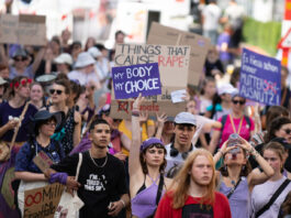 Bonnes nouvelles en septembre, de l’avortement pris en charge à l’atmosphère terrestre Vue d’une manifestation en plein air où un groupe divers de personnes marche dans la rue. Au centre, une jeune femme en haut violet lève une pancarte « My body, my choice ». Plusieurs manifestant·e·s autour portent des vêtements et accessoires violets et tiennent d’autres slogans (dont, en arrière-plan, « Things that cause rape : »). L’ambiance est estivale, la foule avance unie pour défendre les droits à l’avortement et l’autodétermination.