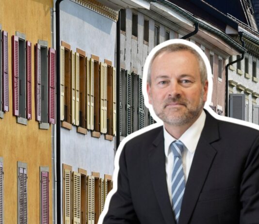 « Les propriétaires ne pourront plus agir sans scrupules » Illustration : un homme en costume-cravate, en surimpression au premier plan, fait face à une rangée de façades de logements anciens aux murs jaune, blanc et pastel, agrémentées de volets colorés (rouges, verts, jaunes).