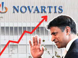 Médicaments : Novartis demande encore plus d’argent malgré des prix déjà élevés Montage photographique : en arrière-plan, la façade d’un immeuble gris clair arbore en grand le logo et le nom « NOVARTIS ». En surimpression, une flèche rouge zigzaguant de l’angle inférieur gauche vers l’angle supérieur droit symbolise une forte progression. Au premier plan, sur la droite, un homme en costume sombre, de profil, lève la main comme pour saluer.