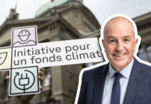 « Nous avons besoin d’investissements supplémentaires dans les infrastructures » Sur la droite, Roland Fischer, souriant en costume-cravate en buste, détouré sur un fond extérieur. À gauche, une main tient une pancarte blanche ornée de trois pictogrammes (un ouvrier au casque, une feuille, une prise électrique) et portant l’inscription “Initiative pour un fonds climat”. En arrière-plan, flou, la façade en pierre du Palais fédéral, coiffé d’un dôme, sous un ciel nuageux.