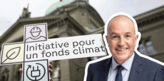 Sur la droite, Roland Fischer, souriant en costume-cravate en buste, détouré sur un fond extérieur. À gauche, une main tient une pancarte blanche ornée de trois pictogrammes (un ouvrier au casque, une feuille, une prise électrique) et portant l’inscription “Initiative pour un fonds climat”. En arrière-plan, flou, la façade en pierre du Palais fédéral, coiffé d’un dôme, sous un ciel nuageux.