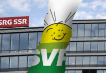 Initiative anti-SSR : l’UDC s’inspire d’une stratégie internationale pour démanteler les médias publics Photomontage montrant la façade vitrée du siège de la SSR avec son logo rouge “SRG SSR”, traversée d’une large déchirure verticale qui laisse apparaître en arrière-plan une bannière verte à l’effigie de l’UDC, ornée d’un soleil stylisé souriant.