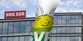 Initiative anti-SSR : l’UDC s’inspire d’une stratégie internationale pour démanteler les médias publics Photomontage montrant la façade vitrée du siège de la SSR avec son logo rouge “SRG SSR”, traversée d’une large déchirure verticale qui laisse apparaître en arrière-plan une bannière verte à l’effigie de l’UDC, ornée d’un soleil stylisé souriant.