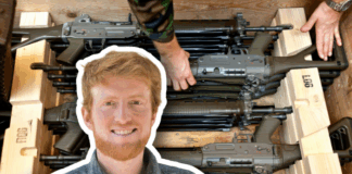 Loi sur le matériel de guerre : « Plus il y a d’armes en circulation, plus le danger pour les civils augmente » Portrait détouré en médaillon d’un homme roux souriant, chemise à carreaux, superposé sur l’image d’arrière-plan montrant plusieurs fusils d’assaut empilés dans des caisses en bois, deux mains en uniforme les ajustant.