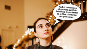 Portrait d’une femme regardant vers le haut, assise à une table de dîner décorée de guirlandes et de lumières chaudes, avec des bougies en arrière-plan. Une bulle de bande dessinée dit : « André, tu racontes n’importe quoi ! On bénéficie énormément de la libre circulation des personnes. »