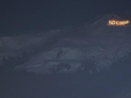 Bonnes nouvelles en janvier : résistance à Davos, le stalking est un délit et l’Espagne introduit un AG à 60 euros Vue nocturne d’un versant montagneux sombre sous un ciel étoilé. Sur une crête à droite, un message lumineux en lettres incandescentes affiche « NO KINGS », se détachant nettement sur le relief obscur.