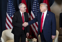 Trump et les droits de douane : la Suisse est dorénavant désavantagée Deux hommes, Guy Parmelin et Donald Trump, en costume-cravate se serrent la main devant plusieurs drapeaux (États-Unis et Suisse). L’un porte un costume bleu foncé et une cravate rouge unie, l’autre un costume sombre et une cravate rouge à petits motifs. À l’arrière-plan, deux fauteuils blancs et une petite table basse ornée d’un bouquet et de verres.