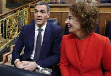 Contre-courant humain : l’Espagne veut régulariser un demi-million de migrant-es Espagne : deux personnes assises côte à côte dans un hémicycle aux boiseries et rambardes dorées. À gauche, Pedro Sánchez, Premier ministre espagnol, un homme en costume bleu foncé, chemise blanche et cravate grise, semble prendre la parole. À droite, sa première vice-première ministre, Maria Jesus Montero, une femme portant un tailleur rouge sourit en le regardant.