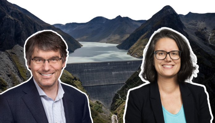 Fonds climat - Oriane- Nordmann Cette image montre deux portraits circulaires superposés devant une vue panoramique d’un barrage et d’un lac de montagne. À gauche, Roger Nordmann, un homme souriant porte une veste sombre et une chemise claire. À droite, Oriane Sarrasin, une femme souriante, vêtue d’une veste noire et d’un haut bleu, porte des lunettes. En arrière-plan, on distingue un grand barrage en béton ainsi qu’un lac entouré de montagnes escarpées, sous un ciel dégagé.