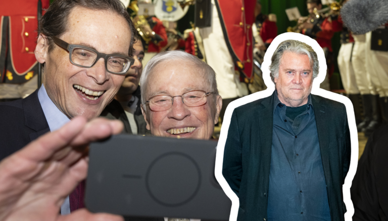 Christoph Blocher et Roger Köppel (UDC), deux hommes d’âge mûr, vêtus de costumes sombres et portant des lunettes, se penchent l’un vers l’autre en souriant pour un selfie : l’un tient un smartphone devant eux. En arrière-plan, un groupe fanfare en uniforme rouge et blanc joue des cuivres sur scène. Sur la droite de l’image, se détache en surimpression le buste de Steve Bannon, un homme d’une cinquantaine d’années, en chemise et veste décontractées, les mains dans les poches, bordé d’un liseré blanc.