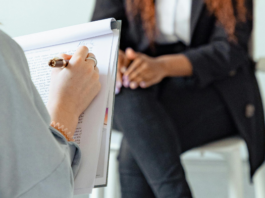 300 000 francs : la Commission des finances vote contre une meilleure aide aux victimes Personne de dos tenant un stylo et un bloc-notes, écrivant des notes manuscrites, en face d’une autre personne assise sur un tabouret, les mains jointes sur les genoux, vêtue d’un tailleur sombre.