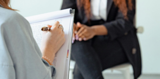 300 000 francs : la Commission des finances vote contre une meilleure aide aux victimes Personne de dos tenant un stylo et un bloc-notes, écrivant des notes manuscrites, en face d’une autre personne assise sur un tabouret, les mains jointes sur les genoux, vêtue d’un tailleur sombre.