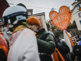Bonnes nouvelles en mars : « No Kings » et le carnaval antifasciste, Pedro Sánchez reste ferme, le service public médiatique reste intact et le PS progresse Une foule de manifestants réunis dans une rue urbaine par temps couvert. Au premier plan, une personne porte un casque décoré et une perruque orange. Au centre, un homme en veste verte tient une pancarte artisanale en forme de cœur orange avec des pompons, sur laquelle est écrit en italien « Siamo tutti antifa scisti » (« Nous sommes tous antifascistes »). Des rubans colorés sont attachés à la pancarte. En arrière-plan, on aperçoit des immeubles et d'autres participants au rassemblement.
