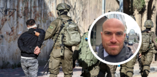 Israël : La peine de mort contre des Palestinien-nes sans procès équitable À l'arrière-plan, des militaires israéliens équipés de gilets tactiques et d'armes encadrent une personne en veste noire, mains attachées dans le dos, face à un mur couvert de graffitis. En superposition, un médaillon circulaire présente le portrait d'un homme d'âge moyen, chauve, avec une barbe courte, photographié dans un environnement urbain.