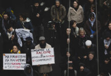 Les agressions racistes continuent d’augmenter L'image montre un groupe de personnes participant à une manifestation à Lausanne après la mort de Marvin. Plusieurs individus tiennent des pancartes avec des messages contre le racisme et la violence policière. Les pancartes portent des inscriptions telles que "Combattre le racisme - Dévoiler un système sans compromis" et "Ma peau n'est pas un costume, ma peau n'est pas une menace #StopBlackFace #StopPoliceViolence". Les manifestants sont vêtus chaudement, suggérant que l'événement a lieu en hiver. L'atmosphère semble sérieuse et déterminée, avec des participants de divers âges et origines ethniques.