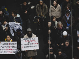 Les agressions racistes continuent d’augmenter L'image montre un groupe de personnes participant à une manifestation à Lausanne après la mort de Marvin. Plusieurs individus tiennent des pancartes avec des messages contre le racisme et la violence policière. Les pancartes portent des inscriptions telles que "Combattre le racisme - Dévoiler un système sans compromis" et "Ma peau n'est pas un costume, ma peau n'est pas une menace #StopBlackFace #StopPoliceViolence". Les manifestants sont vêtus chaudement, suggérant que l'événement a lieu en hiver. L'atmosphère semble sérieuse et déterminée, avec des participants de divers âges et origines ethniques.