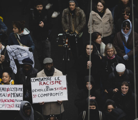 Les agressions racistes continuent d’augmenter L'image montre un groupe de personnes participant à une manifestation à Lausanne après la mort de Marvin. Plusieurs individus tiennent des pancartes avec des messages contre le racisme et la violence policière. Les pancartes portent des inscriptions telles que "Combattre le racisme - Dévoiler un système sans compromis" et "Ma peau n'est pas un costume, ma peau n'est pas une menace #StopBlackFace #StopPoliceViolence". Les manifestants sont vêtus chaudement, suggérant que l'événement a lieu en hiver. L'atmosphère semble sérieuse et déterminée, avec des participants de divers âges et origines ethniques.