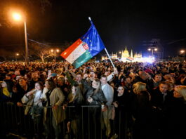 Bonnes nouvelles en avril : Orbán destitué, la LAFE rejetée à Fribourg, la forêt amazonienne est résiliente, le 142 enfin disponible Rassemblement nocturne de milliers de personnes devant le Parlement hongrois à Budapest. Au centre, une personne brandit un drapeau hongrois combiné avec le drapeau de l'Union européenne. La foule, éclairée par des lampadaires, se tient derrière des barrières de sécurité. L'édifice du Parlement illuminé en arrière-plan. Manifestation politique contre Viktor Orbán.