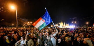 Bonnes nouvelles en avril : Orbán destitué, la LAFE rejetée à Fribourg, la forêt amazonienne est résiliente, le 142 enfin disponible Rassemblement nocturne de milliers de personnes devant le Parlement hongrois à Budapest. Au centre, une personne brandit un drapeau hongrois combiné avec le drapeau de l'Union européenne. La foule, éclairée par des lampadaires, se tient derrière des barrières de sécurité. L'édifice du Parlement illuminé en arrière-plan. Manifestation politique contre Viktor Orbán.
