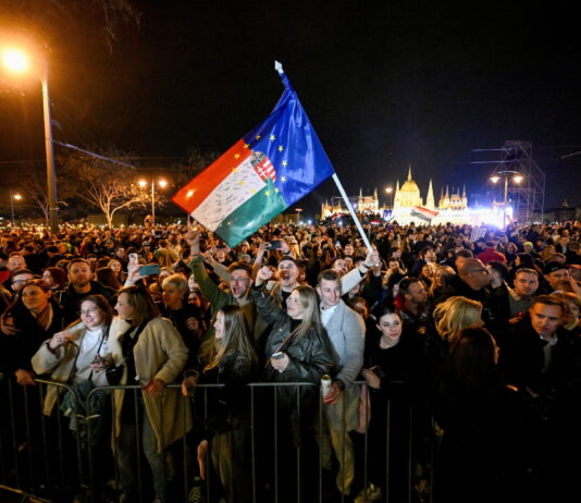 Bonnes nouvelles en avril : Orbán destitué, la LAFE rejetée à Fribourg, la forêt amazonienne est résiliente, le 142 enfin disponible Rassemblement nocturne de milliers de personnes devant le Parlement hongrois à Budapest. Au centre, une personne brandit un drapeau hongrois combiné avec le drapeau de l'Union européenne. La foule, éclairée par des lampadaires, se tient derrière des barrières de sécurité. L'édifice du Parlement illuminé en arrière-plan. Manifestation politique contre Viktor Orbán.