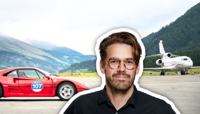 Un homme aux cheveux bruns, portant des lunettes à montures écailles et une chemise noire, est représenté en détourage au premier plan. En arrière-plan, une Ferrari F40 rouge arborant le numéro 107 est garée sur le tarmac d'un aéroport alpin, avec un jet privé blanc et des montagnes verdoyantes sous un ciel dégagé.