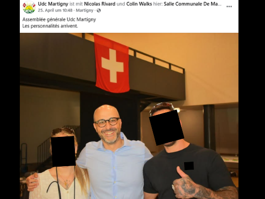 L’UDC montre une fois de plus sa proximité avec l’extrême droite Publication Facebook de l'UDC Martigny du 25 avril. Photo de trois personnes posant devant un bâtiment avec un drapeau suisse rouge et blanc. Les visages de deux personnes sont pixelisés. La légende indique : 'Assemblée générale Udc Martigny - Les personnalités arrivent.'