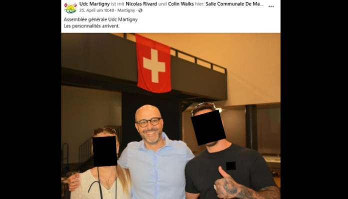 Publication Facebook de l'UDC Martigny du 25 avril. Photo de trois personnes posant devant un bâtiment avec un drapeau suisse rouge et blanc. Les visages de deux personnes sont pixelisés. La légende indique : 'Assemblée générale Udc Martigny - Les personnalités arrivent.'