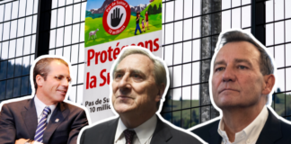 Initiative de l’UDC : les millionnaires et milliardaires s’attaquent aux salaires Montage photographique montrant trois hommes en costume devant un arrière-plan composé d'une grille métallique et d'une affiche politique suisse. L'affiche, visible au centre, porte le slogan "Protégeons la Suisse" avec un panneau "Pas de Suisse à 10 millions" et un pictogramme représentant une main stop rouge. Il s'agit d'une affiche liée à l'initiative populaire suisse contre la surpopulation.