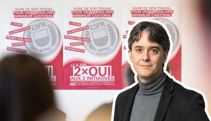 Une personne portant un blazer noir et un col roulé gris se tient devant des affiches de campagne électorale. Les affiches, sur fond rose et blanc, présentent des pièces de monnaie et du texte en français relatif à des initiatives politiques, notamment "2×OUI AUX 2 INITIATIVES". Le message principal porte sur des thèmes sociaux comme le travail, la santé et les allocations familiales, avec mention d'un salaire minimum cantonal.