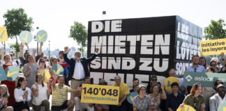 Les loyers sont trop élevés : l’initiative sur les loyers est déposée Manifestation de soutien aux locataires en Suisse. Une foule de manifestants se rassemble devant une grande pancarte noire portant le texte "DIE MIETEN SIND ZU HOCH" (Les loyers sont trop élevés). Au centre, un panneau jaune indique "140'048 Unterschriften" (140 048 signatures). Les participants, dont certains tiennent des symboles jaunes et bleus, posent ensemble pour montrer leur mobilisation contre la crise du logement. Des bannières des organisations "Initiative les loyer" et "asloca" sont visibles, témoignant de l'engagement collectif pour des loyers plus abordables.