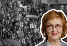 Þórunn Sveinbjarnardóttir : « La grève des femmes nous a montré ce qu’il est possible de faire lorsque les femmes font preuve de solidarité » Portrait d'une femme aux cheveux roux ondulés portant des lunettes rondes et du rouge à lèvres rose, souriant légèrement à la caméra. Elle porte un haut gris. Son portrait est détouré et superposé sur une photographie en noir et blanc historique montrant une foule dense de manifestants tenant des pancartes lors d'un rassemblement public dans une rue urbaine en Islande.