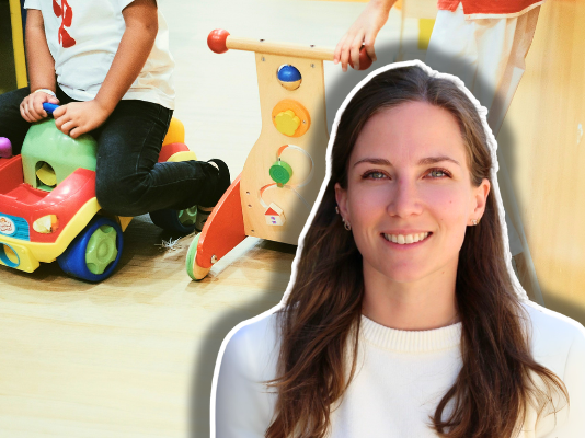 « Les crèches sont enfin devenues politiques » — Journal d’une éducatrice #6 Femme aux cheveux longs, souriante à la caméra, vêtue d'un pull blanc crème, composée sur une image d'arrière-plan montrant un jeune enfant en train de jouer avec des jeux éducatifs colorés : un porteur jouet rouge et jaune avec des roues, et un jouet de frappe en bois avec des perles de couleurs.